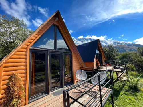 a log cabin with a large glass window and a deck at Kazbegi Kuro Cottages in Stepantsminda