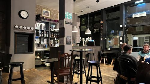 people sitting at a bar with a clock on the wall at Bell House Hostel in London