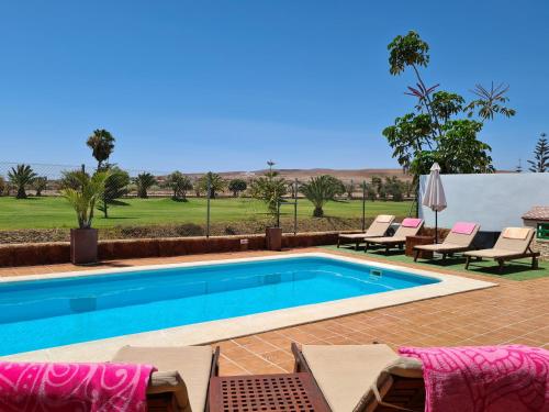 a swimming pool with chaise lounges and chairs around it at Beautiful Villa Grace, Caleta de Fuste in Caleta De Fuste