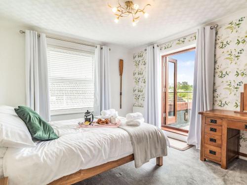 a white bedroom with a bed and a window at Riversdelle in Beccles