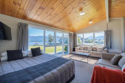 a bedroom with a bed and a couch and windows at Te Anau Motel & Apartments in Te Anau