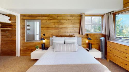 1 dormitorio con cama blanca y paredes de madera en Marketplace Lodge by Whistler Premier, en Whistler