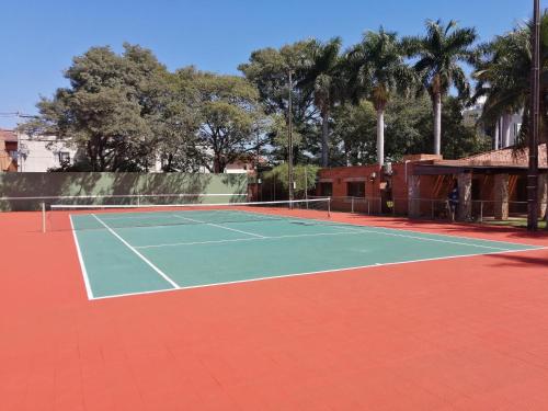 a tennis court with palm trees in the background at BauHouse Comfort Suites Asuncion in Asuncion