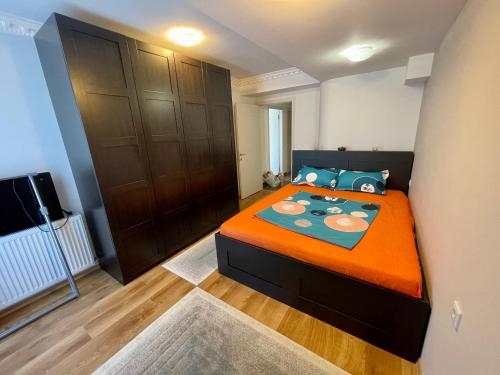 a bedroom with a large bed with an orange blanket at Terrace apartments otopeni ! in Otopeni