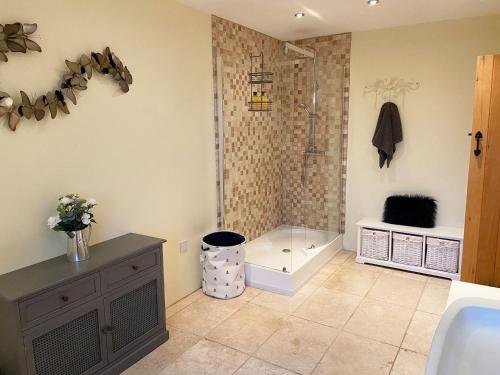 a bathroom with a shower and a bath tub at Coed Y Nant Barn in Cilybebyll