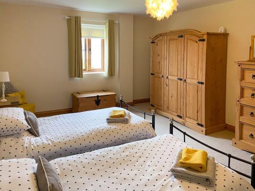 a bedroom with two twin beds and a dresser at Coed Y Nant Barn in Cilybebyll