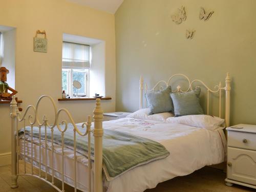 a bedroom with a white bed and a window at Bryn Ysgol in Yspytty-Ifan