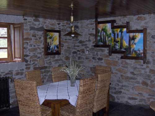 Casa da Janal في Vimioso: غرفة طعام مع طاولة وكراسي وجدار حجري