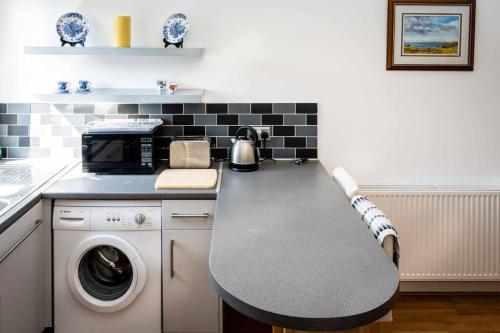 a kitchen with a table and a washing machine at Charming 1-bed Southside Flat in Great Location in Kings Park