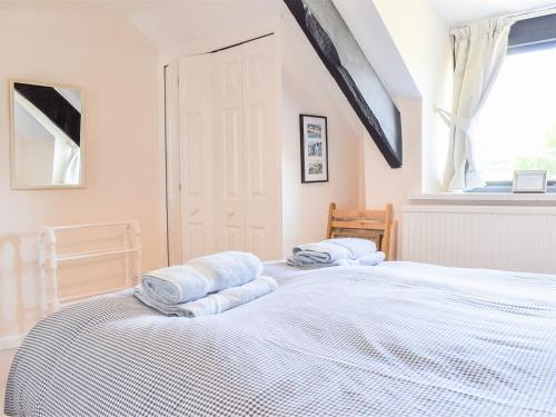 a bedroom with a bed with blue towels on it at Thorntree Cottage in Colaton Raleigh