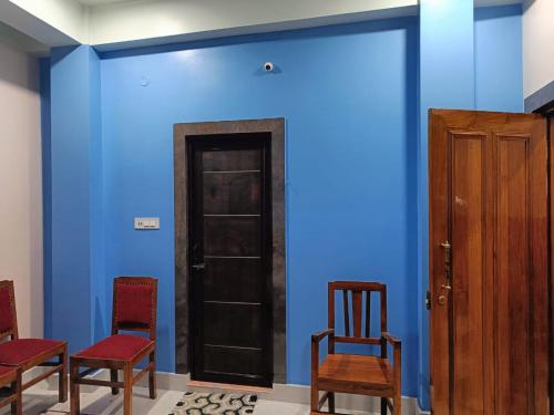 a room with blue walls with chairs and a door at Ujjayanta Homestay in Agartala