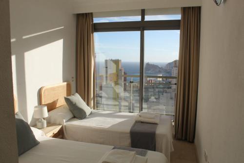 ベニドルムにあるApartamento el Cielo de Benidormのベッド2台と大きな窓が備わるホテルルームです。