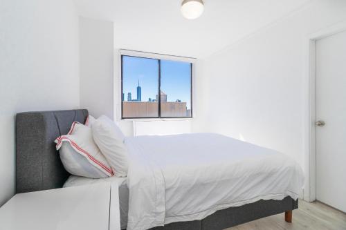 LUXURY DESIGNER GREENWICH VILLAGE 1BR HEAVEN!! BEAUTIFUL PANORAMIC CITY VIEWS! في نيويورك: غرفة نوم بيضاء بها سرير ونافذة