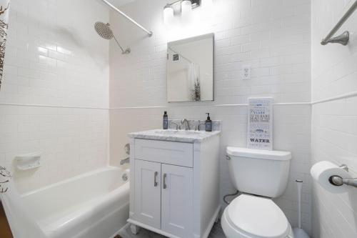 LUXURY DESIGNER GREENWICH VILLAGE 1BR HEAVEN!! BEAUTIFUL PANORAMIC CITY VIEWS! في نيويورك: حمام ابيض مع مرحاض ومغسلة وحوض استحمام