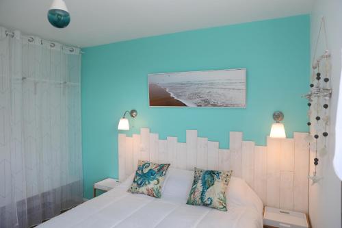 1 dormitorio con cama blanca y pared azul en Les Chalets du Bois Blanc, 