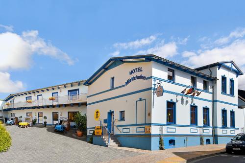 ein weißes Gebäude mit blauem Trimm auf einer Straße in der Unterkunft Hotel Am Müritzhafen garni in Waren (Müritz)