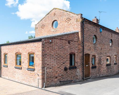 an old brick building with windows on the side at No1 Little Barrow Barns - Sleeps 10 in Chester