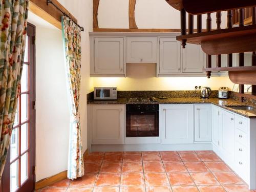cocina con armarios blancos y suelo de baldosa en Fochy Cottage en Milnathort