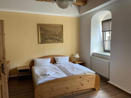 a bedroom with a bed with white sheets and a painting on the wall at Braugut Hartmannsdorf in Hartmannsdorf