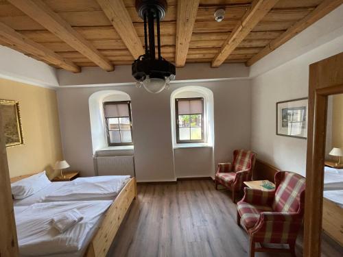 a room with two beds and two chairs in it at Braugut Hartmannsdorf in Hartmannsdorf