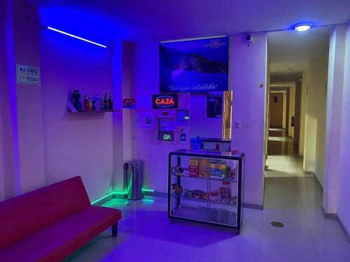 een kamer met een bank en een koelkast met paarse verlichting bij HOSTAL BULEVAR in Piura