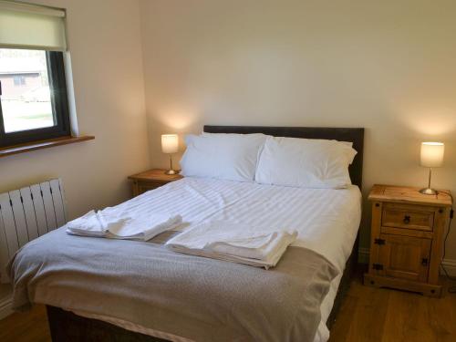 a bedroom with a bed with white sheets and two lamps at Juniper Lodge - UKC3931 in Otterburn