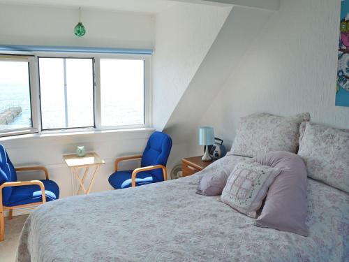 um quarto com uma cama e duas cadeiras azuis em Seascape em Balintore
