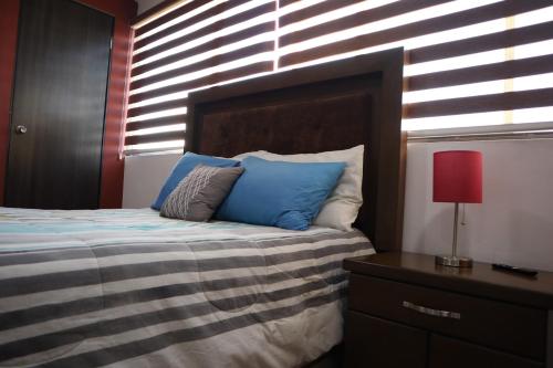 1 dormitorio con 1 cama con almohadas azules y lámpara roja en Departamentos Bonsai en Torreón