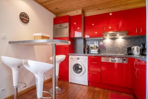 a kitchen with red cabinets and a washer and dryer at Appartement du Poutat - Welkeys in LʼHuez