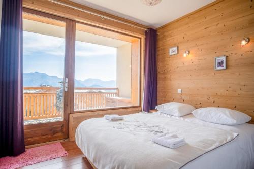 a bedroom with a bed and a large window at Appartement du Poutat - Welkeys in LʼHuez