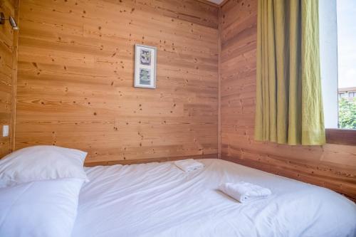 a bed in a wooden room with two towels on it at Appartement du Poutat - Welkeys in LʼHuez
