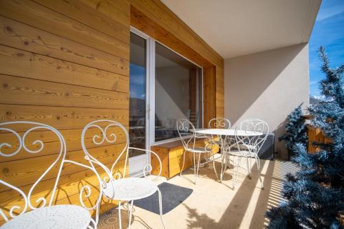 een balkon met witte stoelen en tafels en een raam bij Superb apartment with balcony in the heart of Huez - Welkeys in Huez