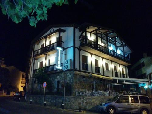 a building with a car parked in front of it at Hostal La Maya in Cercedilla