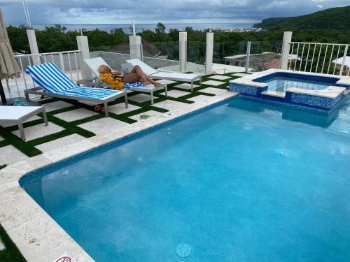 a woman laying in a chair next to a swimming pool at Luxury Studio Rooftop Pool n View unit #4 in Falmouth