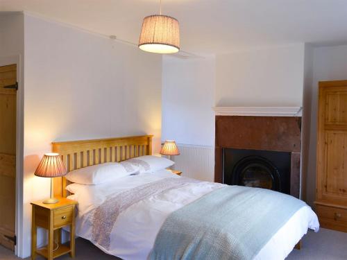 a bedroom with a bed with two lamps and a fireplace at Seventeen Ten in Castle Carrock