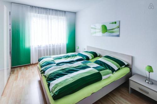 1 dormitorio con 1 cama con sábanas verdes y blancas en Ferienwohnung in Augsburg, en Augsburg