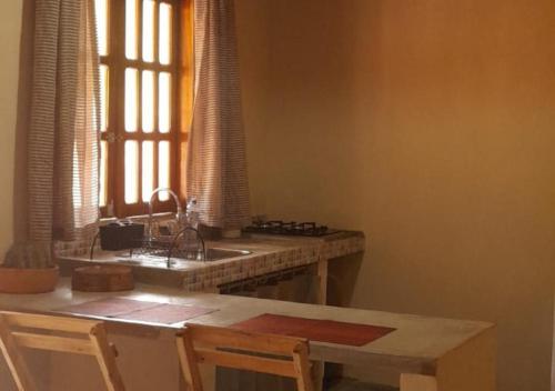 een keuken met een wastafel en een tafel met stoelen bij Vila Sincorá - Chalé para 4 pessoas com cozinha a 2 km da portaria da Cachoeira do Buracão in Ibicoara