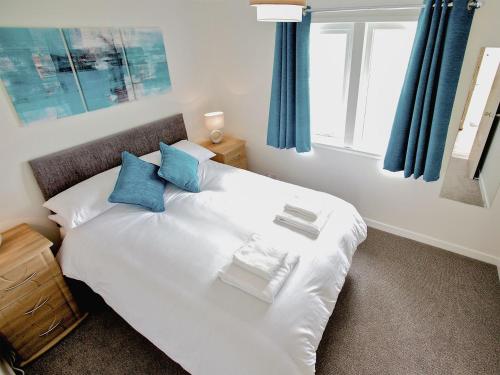 Saint Marys的住宿－Rockworks Chalets No,2 - Uk7041，一间卧室配有白色的床和蓝色窗帘