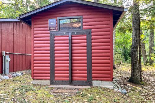 a red shed with a red door in the woods at The Nut House in Eagle River