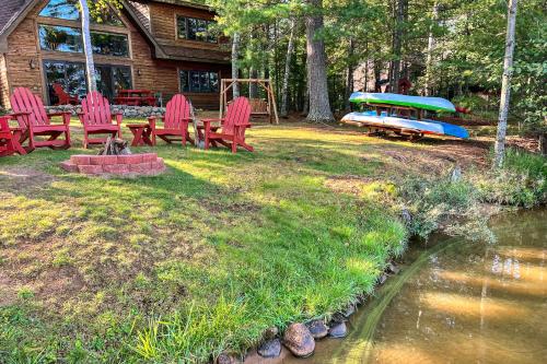 a yard with red chairs and a table and a pond at The Loons Nest in Eagle River