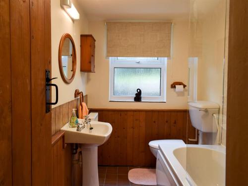 een badkamer met een wastafel, een toilet en een bad bij Augustus Cottage in Rowlstone