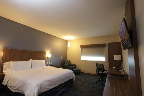 a hotel room with a bed and a flat screen tv at Holiday Inn Express & Suites Mexicali by IHG in Mexicali