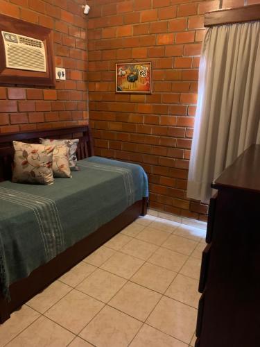 a bedroom with a bed and a brick wall at Casa de Campo Gravata-Pe in Gravatá