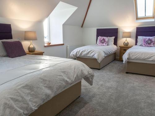 a bedroom with two beds and two windows at Sunset View in Ardmaleish