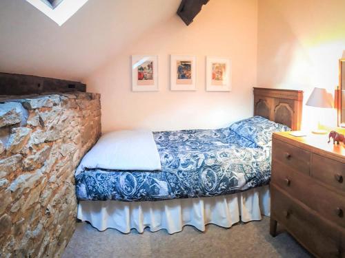 a bedroom with a bed and a stone wall at Jinney Ring in Leintwardine