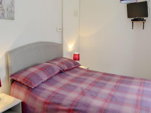 ein Schlafzimmer mit einem Bett mit einer karierten Decke in der Unterkunft Barnhill Bothy in Moffat