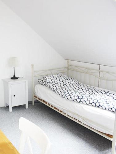 Habitación blanca con cama y mesita de noche en Dejligt værelse lyst og hyggeligt, en Skovlunde