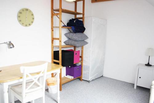 um quarto com uma secretária, uma mesa e um relógio em Dejligt værelse lyst og hyggeligt em Skovlunde