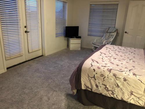 ein Schlafzimmer mit einem Bett und einem Stuhl und Fenstern in der Unterkunft 2 master suites and loft with kitchenette in upper level within our shared townhome in Mesa
