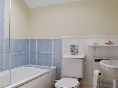 a bathroom with a tub and a toilet and a sink at The Smithy - Ukc3748 in Charmouth
